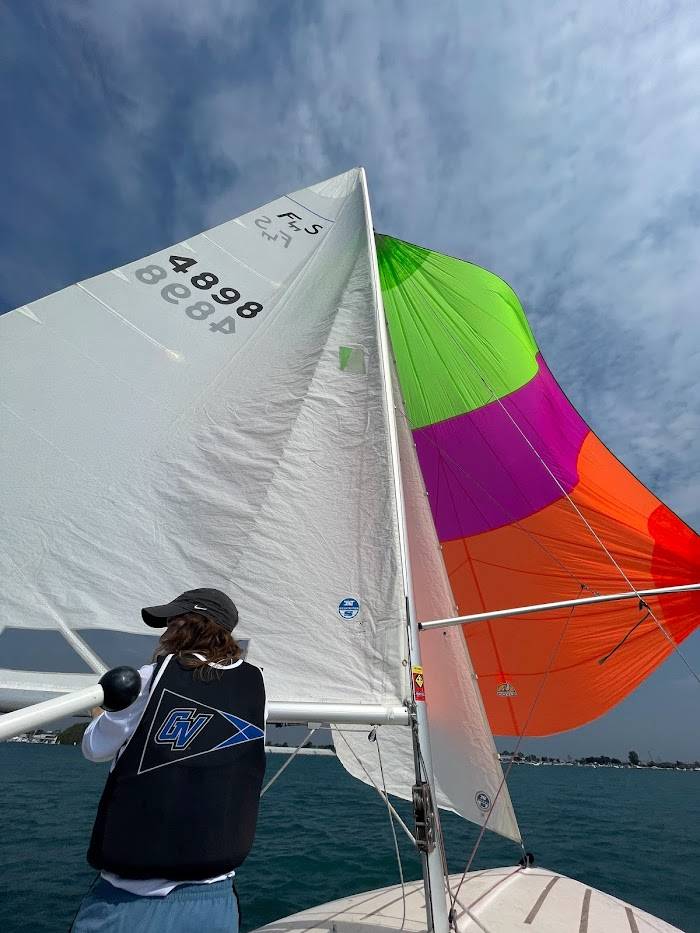 GVSU sailor standing in front of multicolored spinnaker sail.